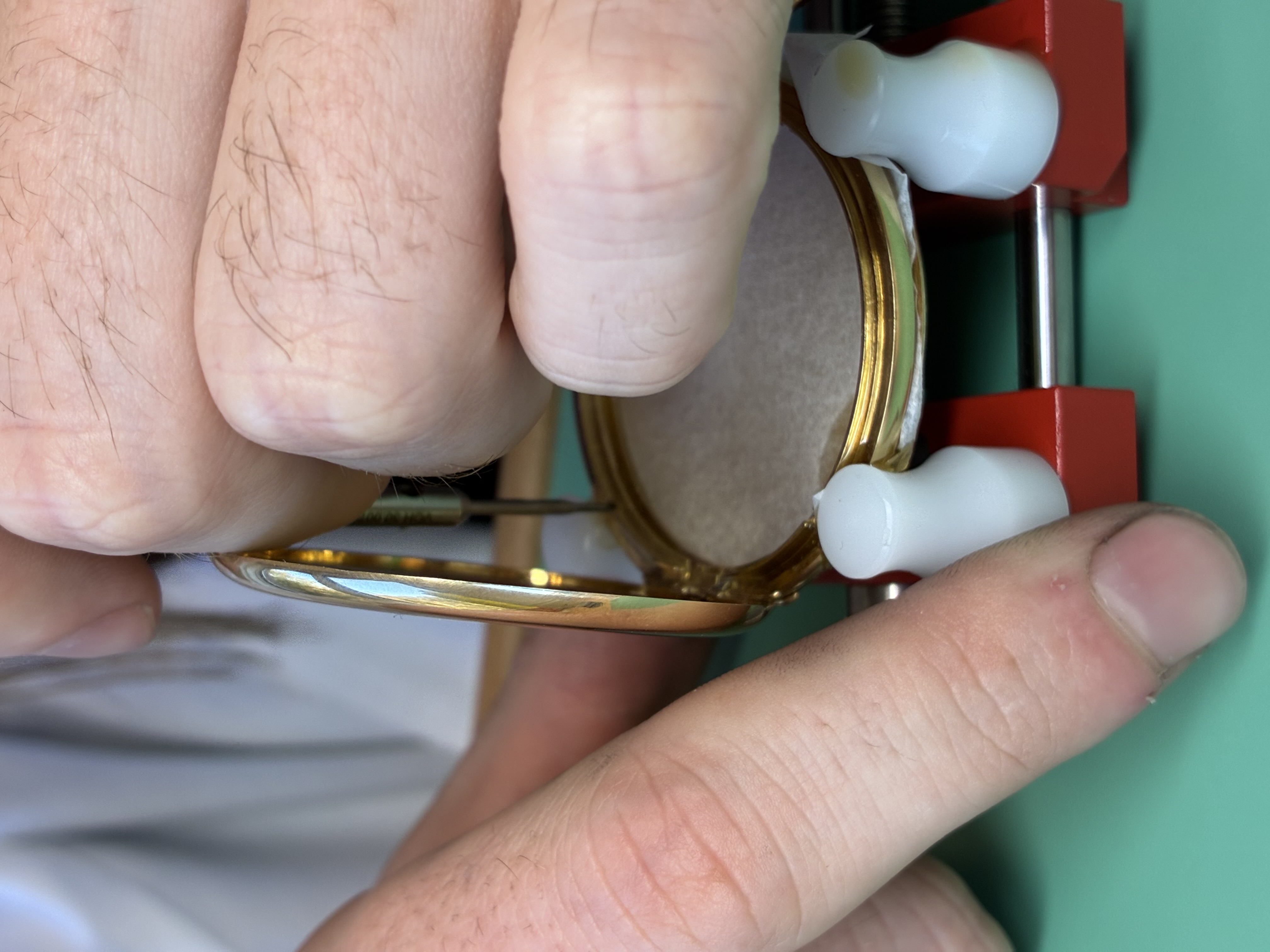 Tapping the gold case to accept the newly made screws.