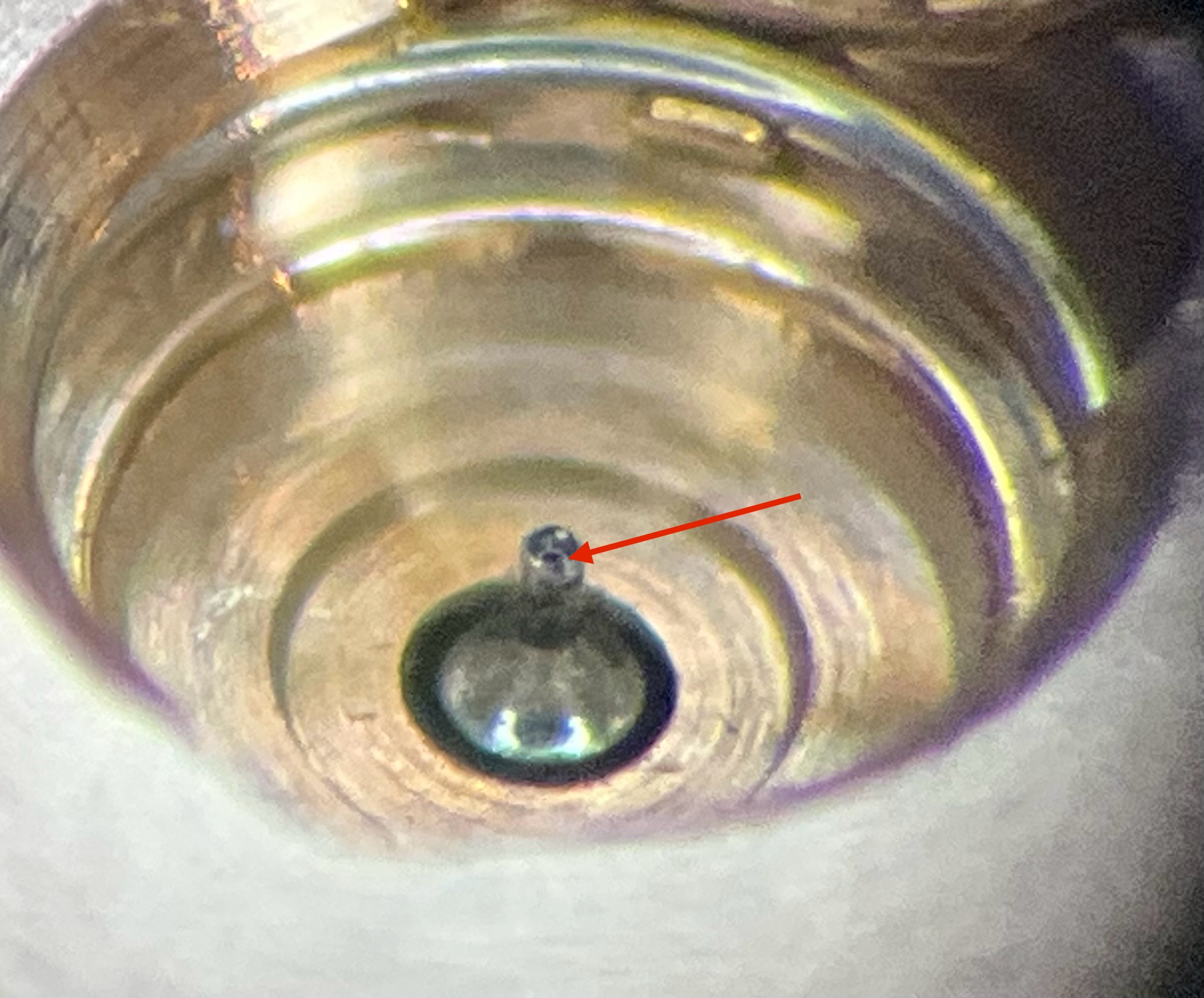 Under magnification: the corroded balance pivot (arrowed) behind the amplitude problem.
